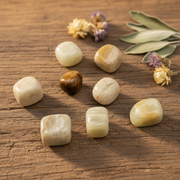 Seven beige stones on a brown table with flowers around the table.