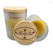 Two containers with wooden lids, one open showing a yellow substance, on a white background. Brand 'Cheeky Bee' visible.