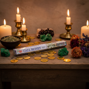 Hem Incense Call Money 20g Approximate  on a table surrounded by coins and herbs, flowers and candles.