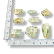 Green crystals on a white surface with a ruler for scale.