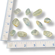 Set of light green gemstones with a ruler for scale on a white background