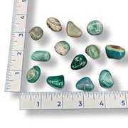 Green and brown stones on a white background with a ruler for scale.