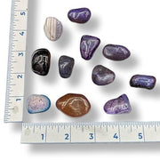 Assorted colorful stones on a white background with a ruler for scale.