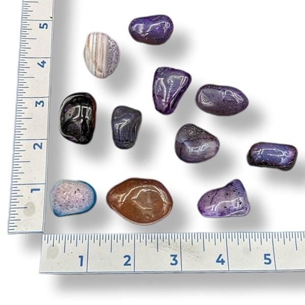 Assorted colorful stones on a white background with a ruler for scale.