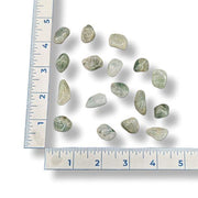 Green gemstones on a white surface with a ruler for scale.