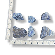 Blue crystals with a ruler for scale on a white background