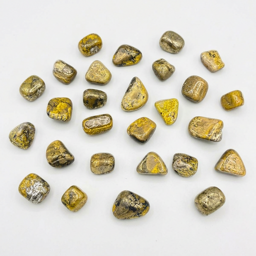 A group of polished tumbled gemstones in yellow, bronze, and silver tones scattered on a plain white background.