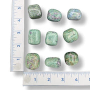 Green glittery stones with a ruler for scale on a white background