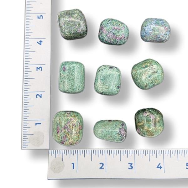 Green glittery stones with a ruler for scale on a white background