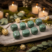 Ruby in kyanite on a wooden plank surrounded by candles and a greenery setting
