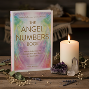 Book titled 'The Angel Numbers Book' with a candle and crystals on a wooden surface.