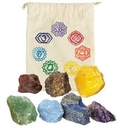 Set of seven raw crystals in various colors with corresponding chakra symbols on a drawstring bag.