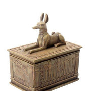 Sandstone coloured statue of a Anubis on a box on a white background