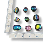 Multicolored stones with iridescent properties on a white background with a ruler for scale.