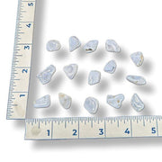 Set of tumbled blue lace agate gemstones next to a ruler on a white background