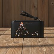 A black leather  pouch with a wrist strap, featuring a painted Native American-style figure with feathers in warm tones, set on a rustic wooden surface against a wooden plank background.