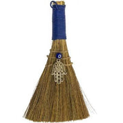 Broom with blue handle and Hamsa charm on a white background