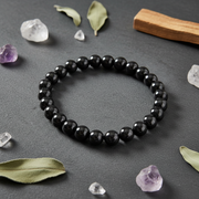 Black beaded bracelet on a dark surface with crystals and leaves