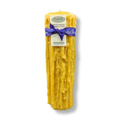 Yellow beeswax product with a purple bow and label on a white background