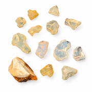 A collection of raw, rough-cut opal gemstones in various shapes and colors, including yellow, blue, green, and orange tones, arranged on a plain white background.
