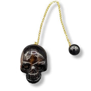 Black skull pendulum with silver chain on a white background
