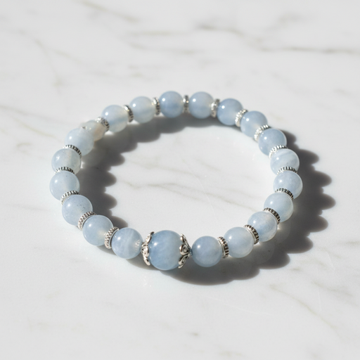 A beaded stretch bracelet made of light blue round beads with silver-toned spacer rings and a central decorative silver bead, displayed on a white marble surface.
