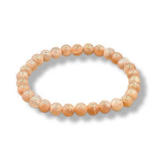 Beaded bracelet with a subtle pattern on peach-colored beads against a white background
