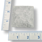 Square selenite plate next to two rulers for scale on a white background