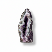 A polished natural geode slice with a dark purple outer matrix and a glittering interior lined with silver and white druzy crystals, shown on a clean white background with a soft drop shadow.
