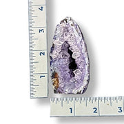 Geode with purple interior next to a ruler on a white background