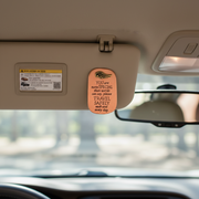 A copper-colored clip with text on a car's sun visor
