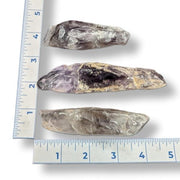 Three stone tools on a ruler for scale on a white background