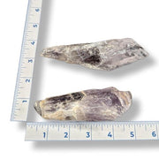Two stone amethyst on a white background with a ruler for scale.