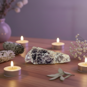 A amethyst crystal with a natural rough texture, showing deep purple and light lavender tones, set against a plain white background with a soft drop shadow.
