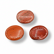 Three polished red jasper worry stones on a white background
