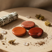 Red jasper worry stone on a wooden piece of wood with sage and herbs