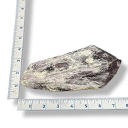 A piece of amethyst next to a ruler on a white background