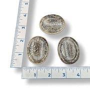 Three smokey quartz worry stones of varying sizes, placed on a white surface, with a ruler for scale.