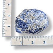 Blue and white stone next to a ruler on a white background