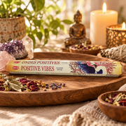 A box of HEM Ondes Positives 'Positive Vibes' incense sticks rests on a wooden tray in a styled setting with candles, crystals, dried flowers, and a Buddha statue in the background.