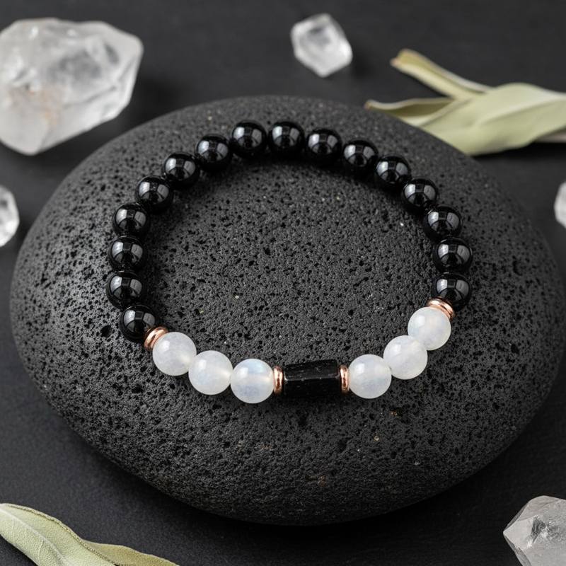 Black and white beaded bracelet on a dark stone surface with crystals around