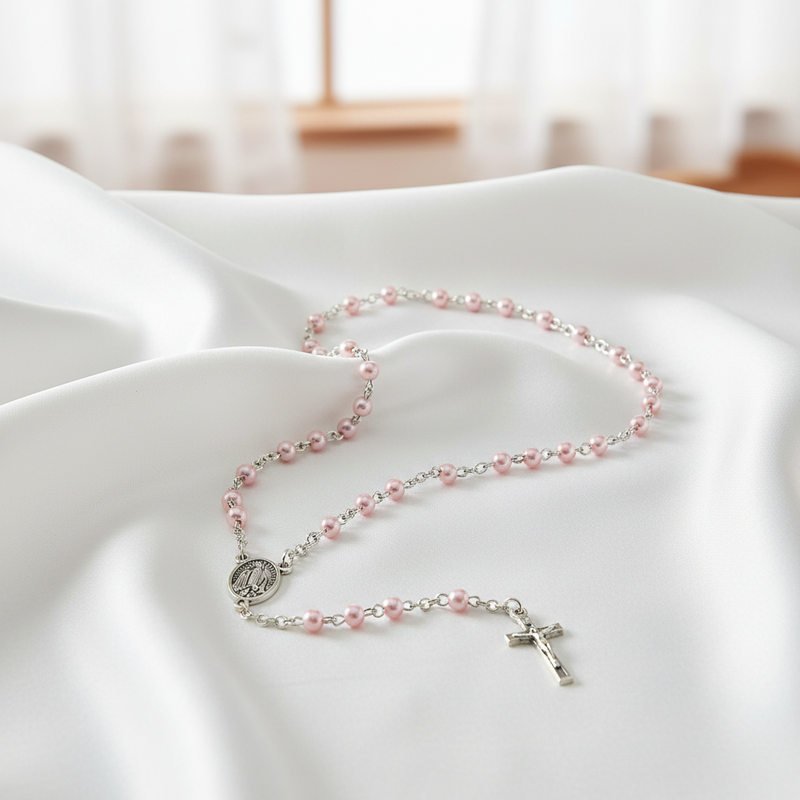 Pink pearl rosary  with a cross on a white cloth surface