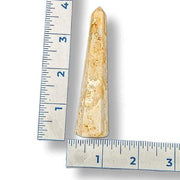 Crystal obelisk next to a ruler on a white background