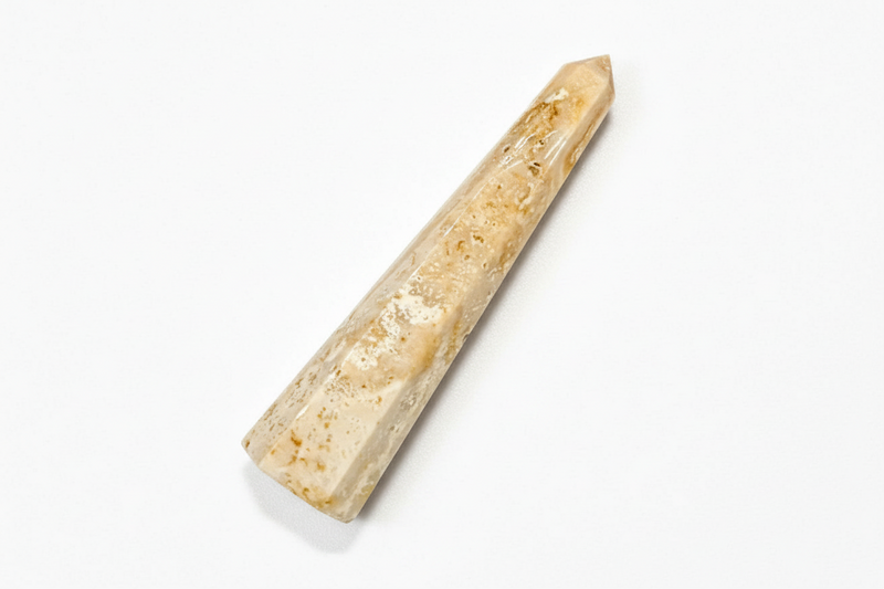 A natural agate obelisk with a warm beige and light brown coloration, displayed diagonally on a clean white background.