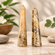Two agate obelisks on a marble table with plants and two river stones.