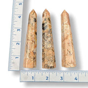 Three crystal sticks with a ruler for scale on a white background
