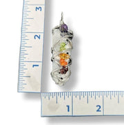 Crystal pendant with colorful stones on a ruler for scale