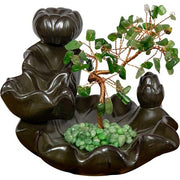 Decorative backflow burner with green stones and a small tree on a white background