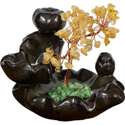 Decorative black ceramic backflow burner with yellow and green stones on a white background