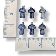 Set of blue mushroom-shaped earrings next to a ruler for scale on a white background